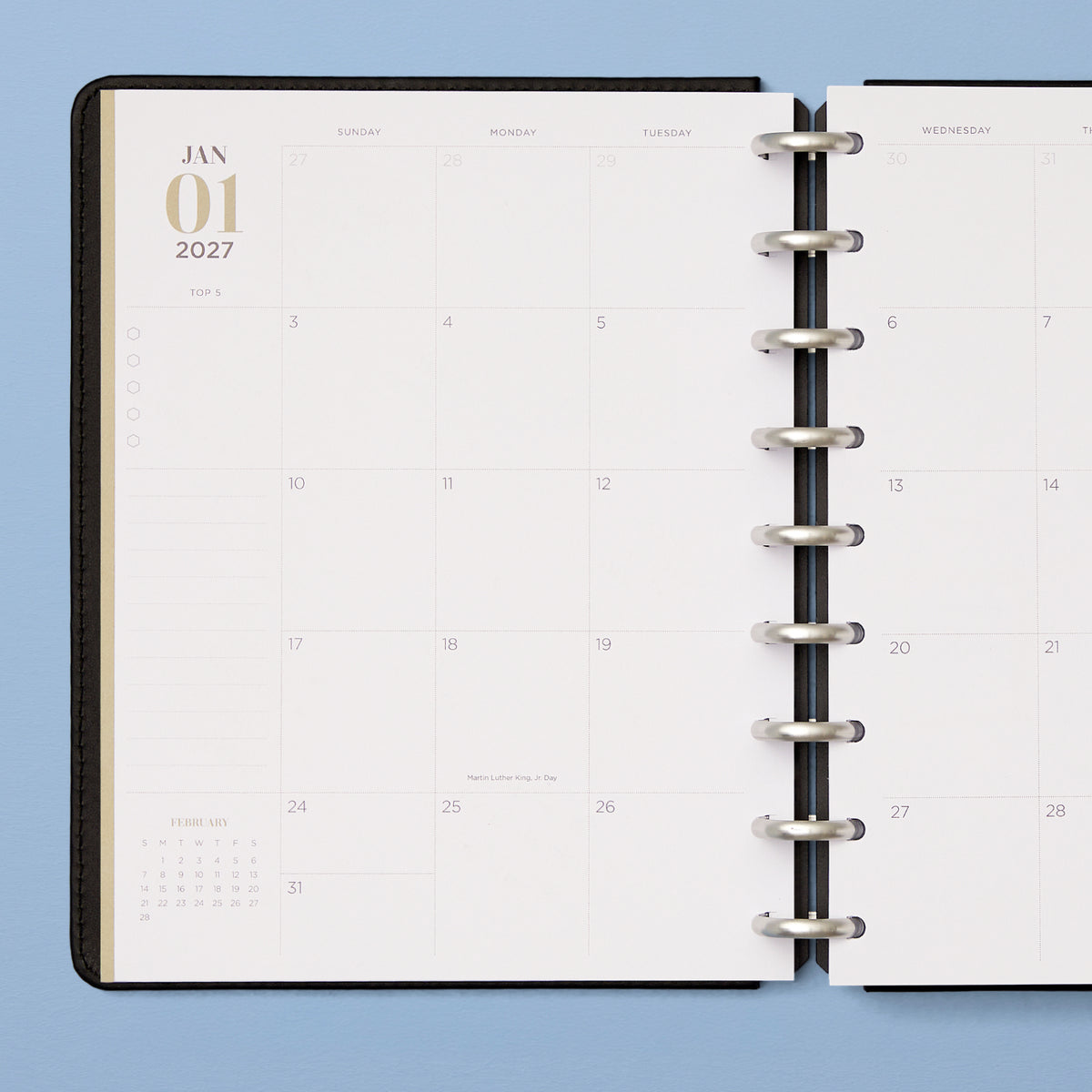 An open disc-bound planner showing a monthly calendar spread with lined notes section and reference calendar, and bullet points
