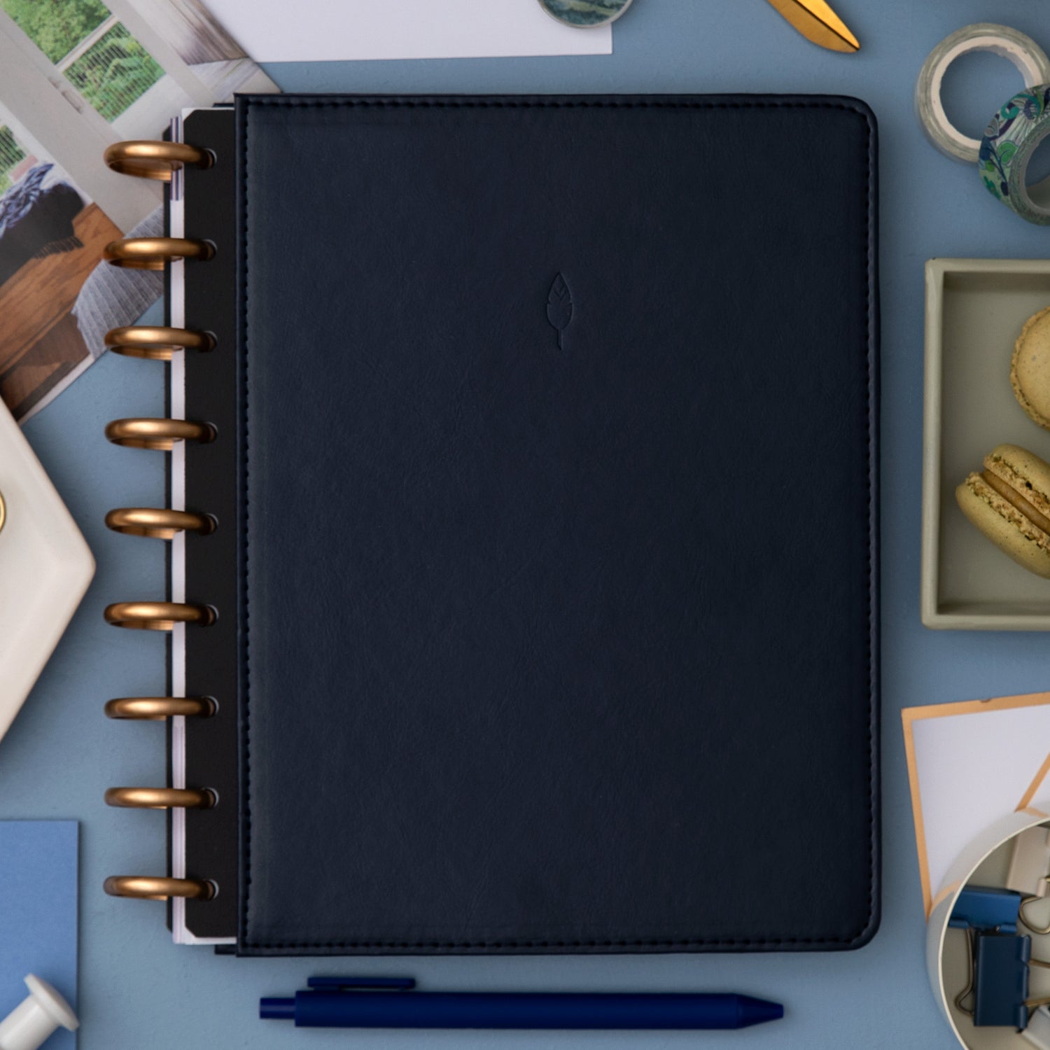 sapphire faux leather cover with gold disc on this inkwell planner surrounded by office supplies