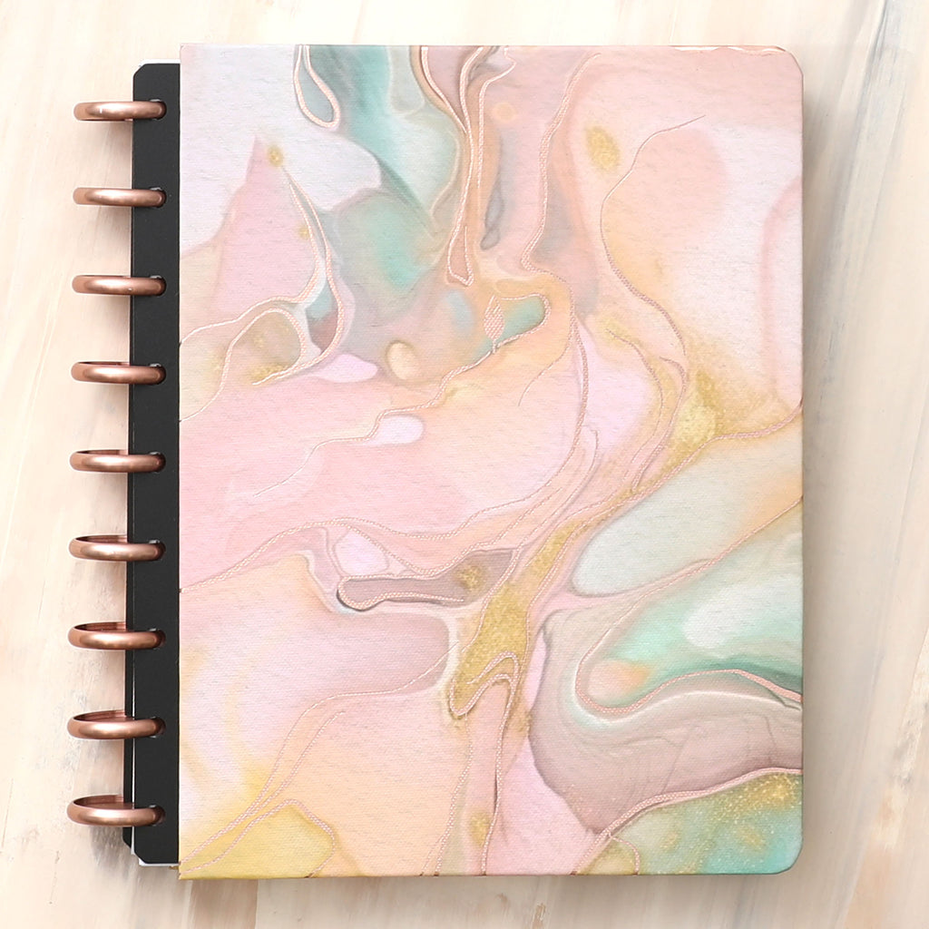 An alcohol ink design in shades of terracotta and pink is the featured hard cover on this inkwell press planner system with rose gold discs 